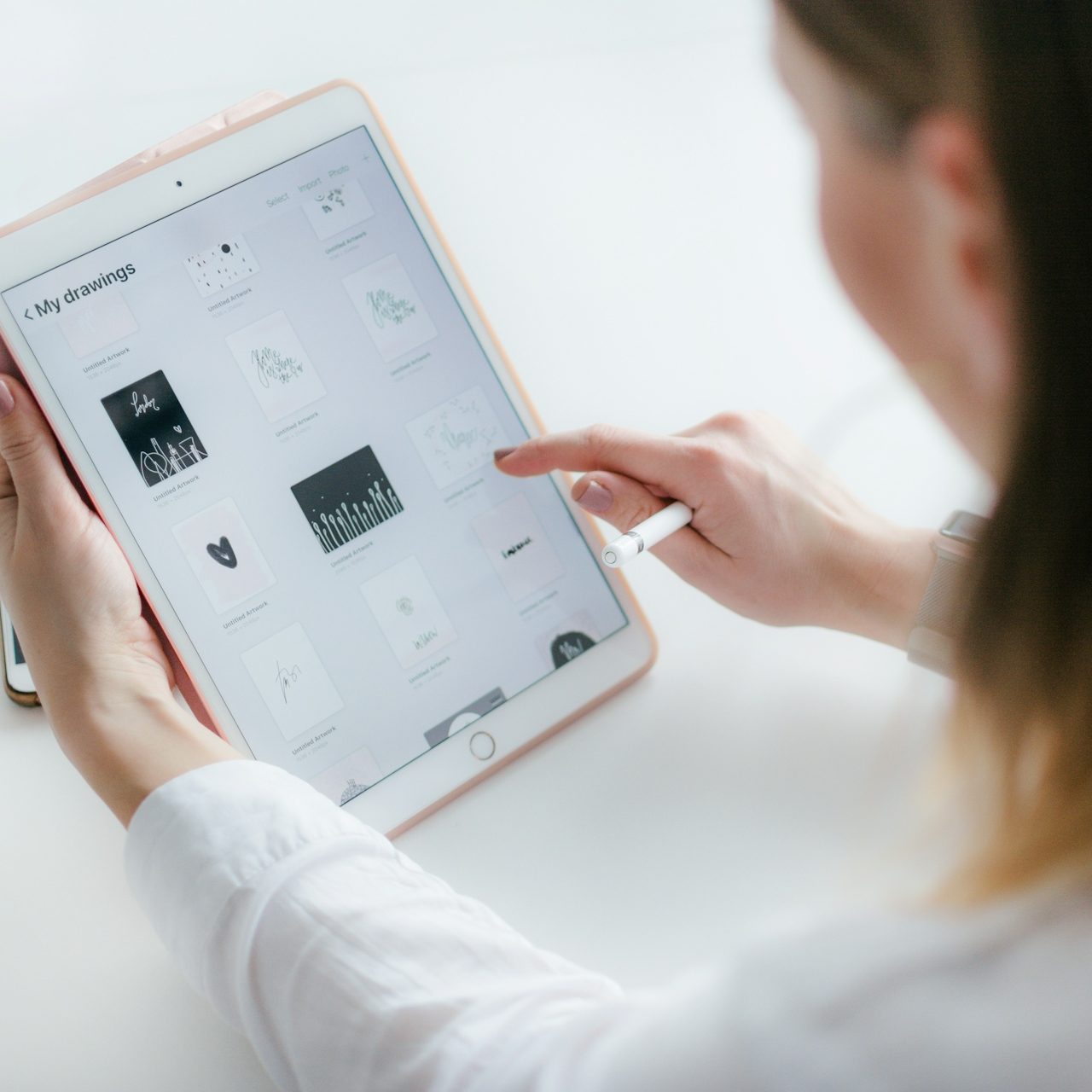 Frau, die mit einem Tablet an einem Tisch arbeitet und den Bildschirm berührt.